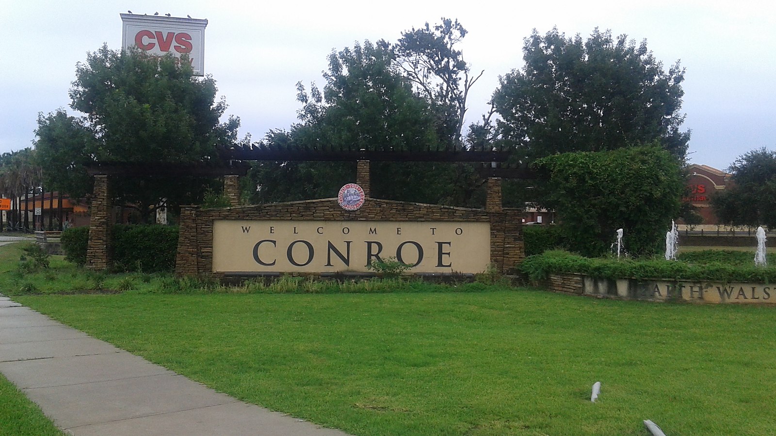 The Welcome to Conroe sign standing on a mown verge with trees behind it — representative imagery, not a specific Texas Pride job