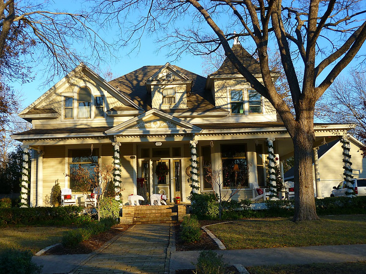 A large older timber-framed Texas house with a deep wraparound porch, seen through bare trees &mdash; representative imagery, not a specific Texas Pride job